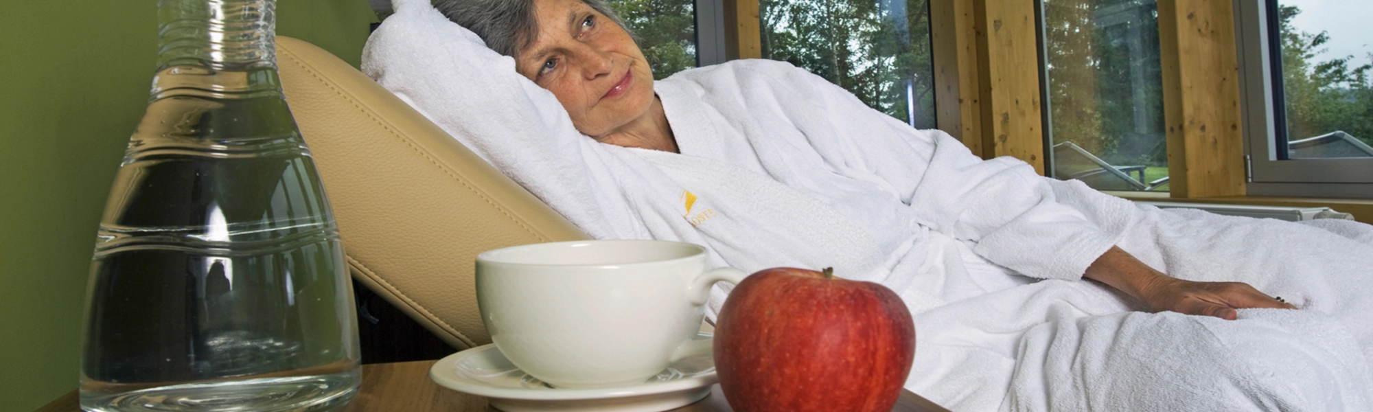 Frau liegt auf Liege. Apfel liegt vor ihr beim Buchingerfasten und Wandern im Kloster Permegg