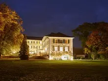 Das Bild zeigt die Fassade des beleuchteten Schloss Burgellern bei Nacht.