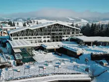 Das Bild zeigt die Außenansicht des verschneiten Hotelbereichs Rosenalp in Oberstaufen.