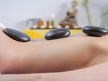 Das Bild zeigt eine Person, die auf ihrem Rücken mit einer Hot Stone Massage verwöhnt wird