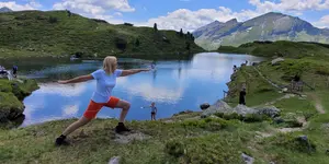 Das Bild zeigt eine Person, die Indian Balance oberhalb des Sees inmitten der Natur praktiziert, Fasten nach Buchinger oder Basenfasten