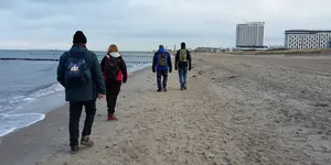 Das Bild zeigt eine Fastenwandergruppe, die am Strand der Ostsee entlang läuft, Fasten nach Buchinger