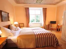 Doppelzimmer mit Bett und Sitzmöglichkeit im Schloss Burgellern in Scheßlitz in Deutschland